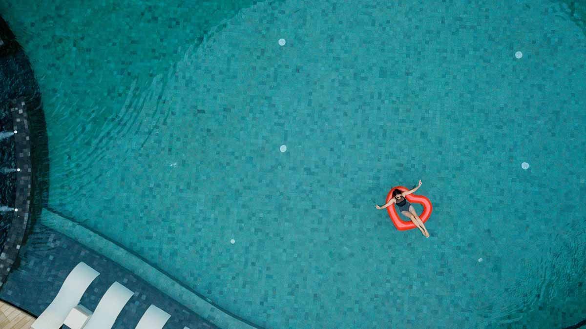 An aerial view of a person in a heart shaped float in a swimming pool.