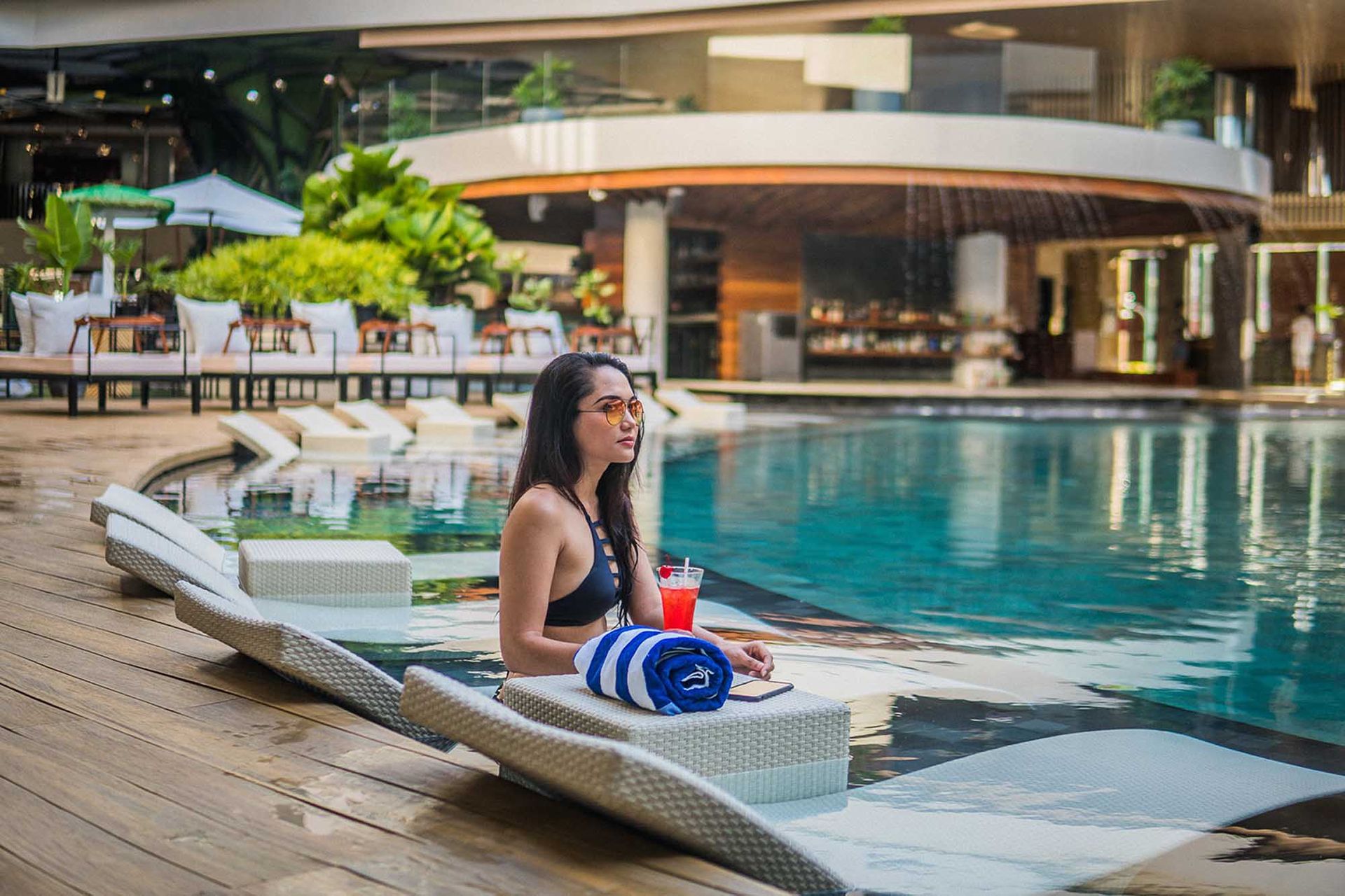 Woman in swimsuit relaxing in pool, holding a drink, with a towel, in Boracay Station 2 hotels with pool