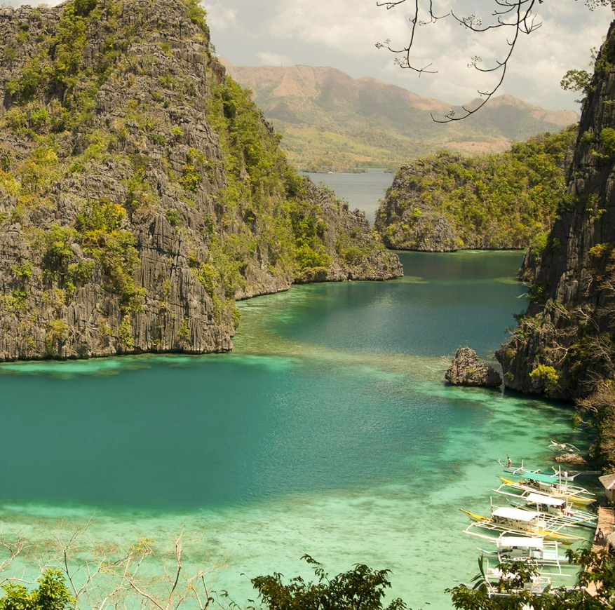 Scenic lagoon view near best Puerto Princesa hotel featuring limestone cliffs, turquoise waters, and traditional bancas
