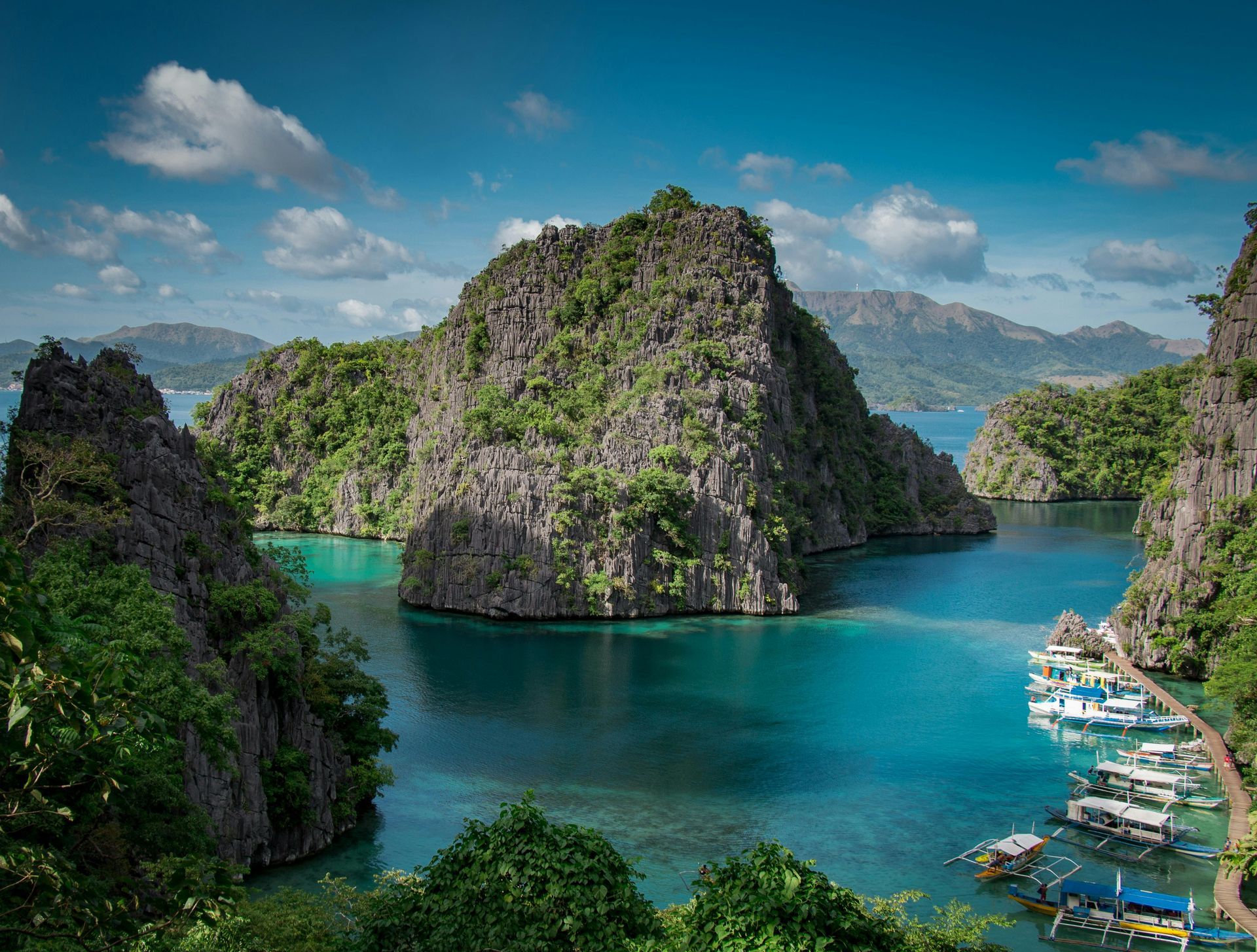 A large body of water surrounded by mountains and trees with boats in it.