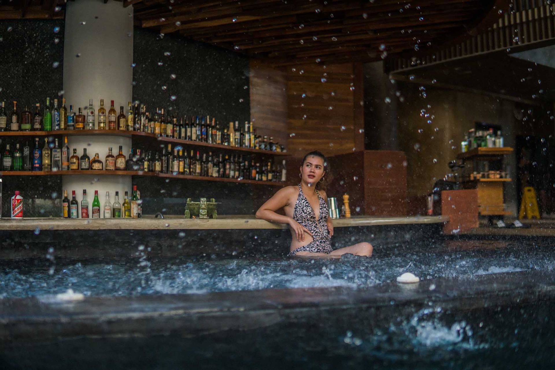 A woman in a swimsuit is sitting in a pool of water.