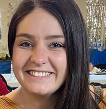 Woman with dark hair, smiling, in front of a party backdrop.