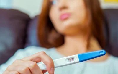 A woman is holding a pregnancy test in her hand.
