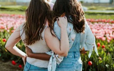 Two women are hugging each other in a field of flowers.