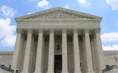 A man is standing in front of the supreme court building.