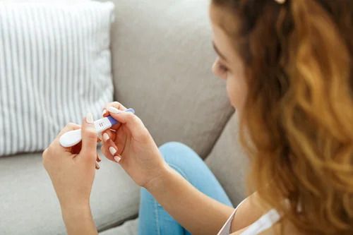 A woman is sitting on a couch holding a pregnancy test.