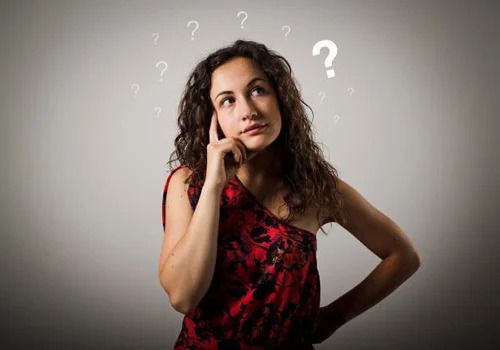 A woman is thinking with question marks around her head.