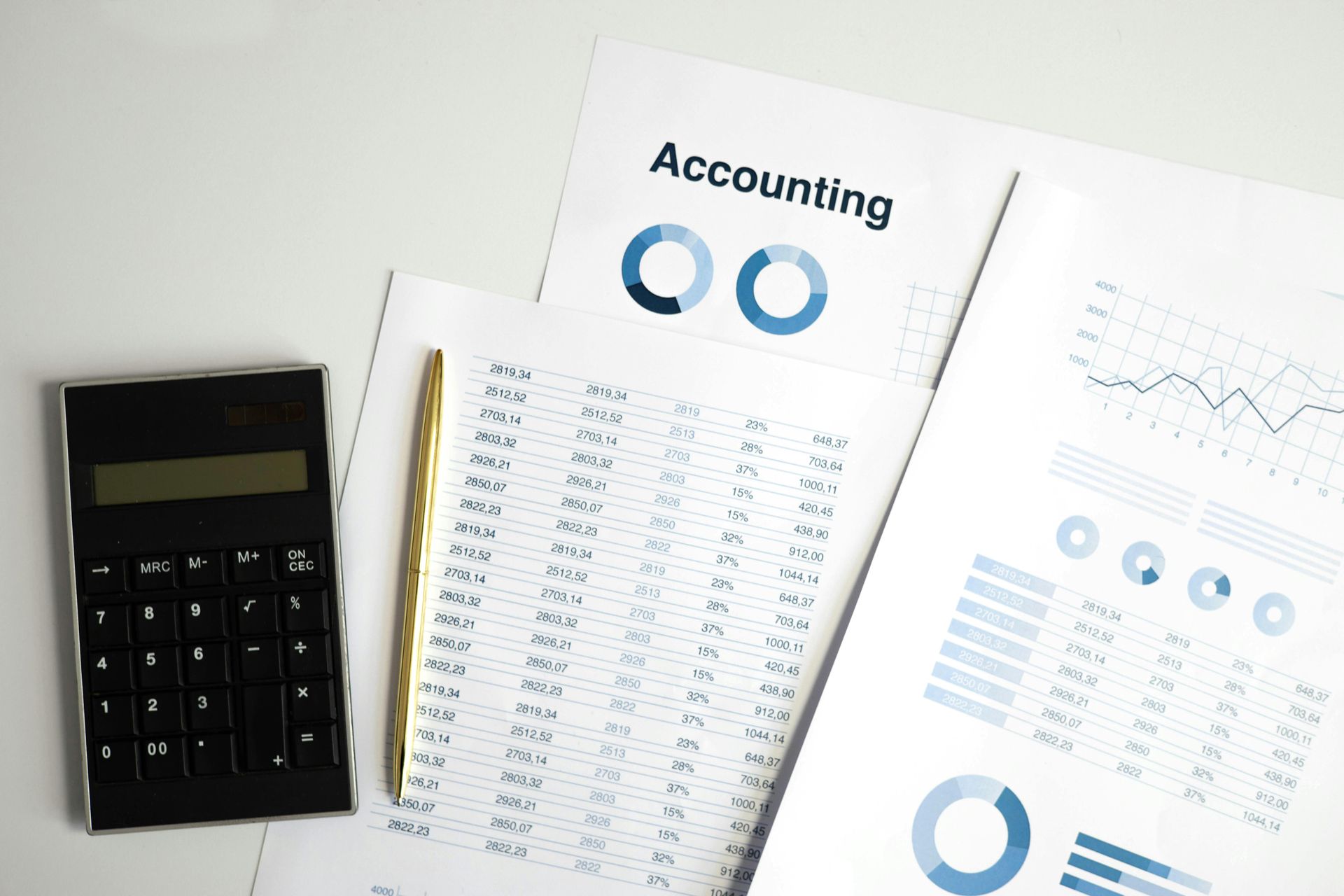 Calculator, pen, and financial documents with charts and tables on a white surface.