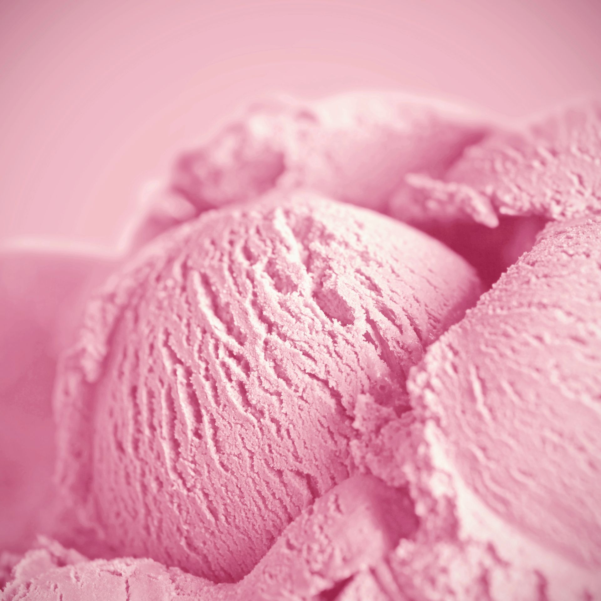 Primo piano di palline di gelato alla fragola rosa con una superficie cremosa e dalla consistenza particolare.