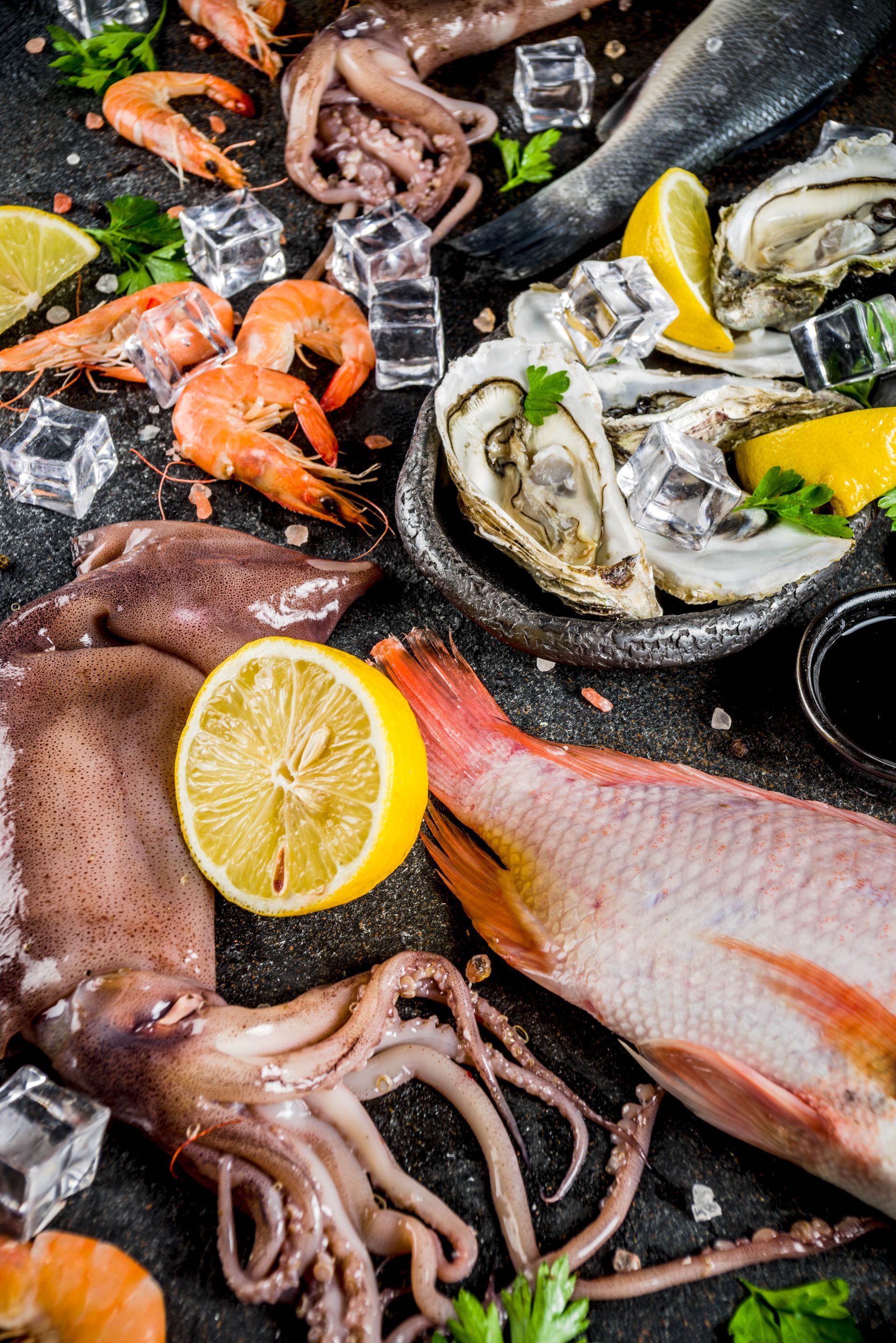 Piatto di frutti di mare con ostriche, gamberi, calamari, pesce e spicchi di limone su ghiaccio