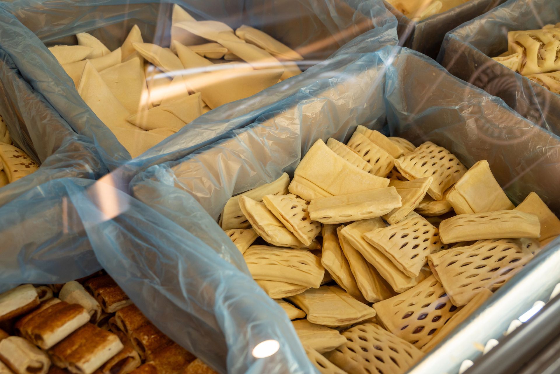 Contenitori di plastica pieni di cracker e grissini assortiti esposti in un mercato.