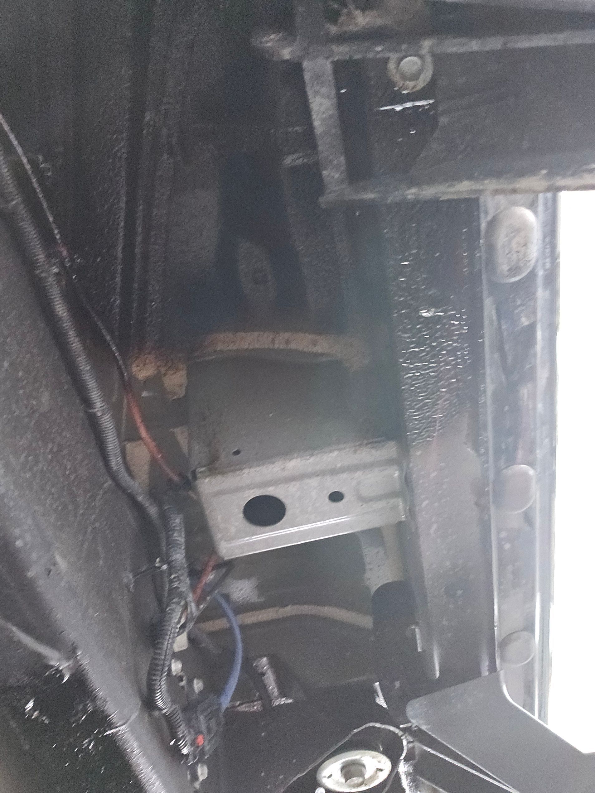 Composant interne du véhicule, probablement une boîte à fusibles, montée dans un boîtier sombre avec câblage.