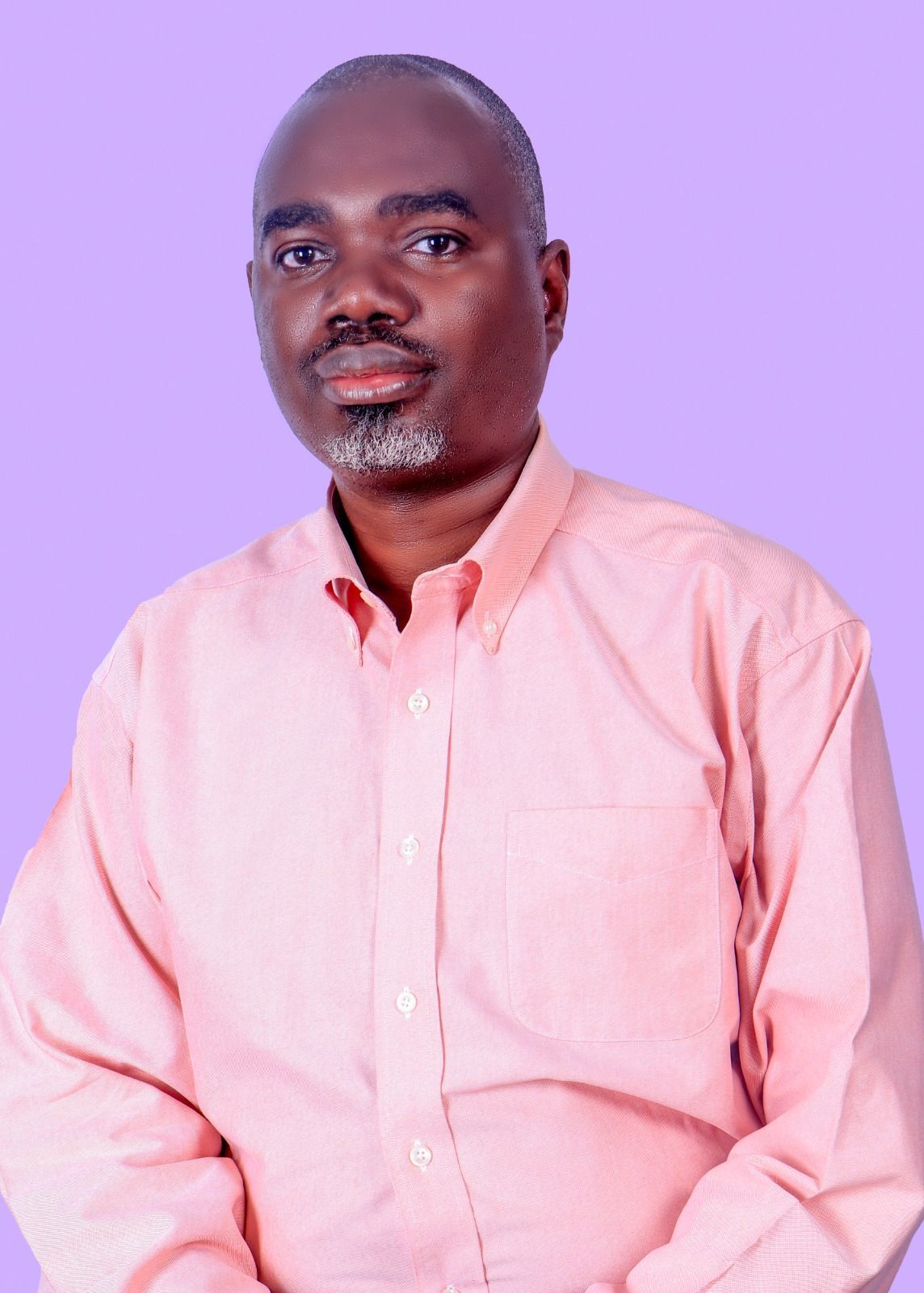 Man in a pink button-down shirt against a lavender background, looking directly at the viewer.