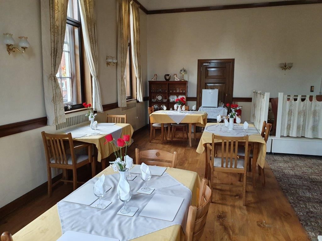A dining room with tables and chairs and flowers on the tables.