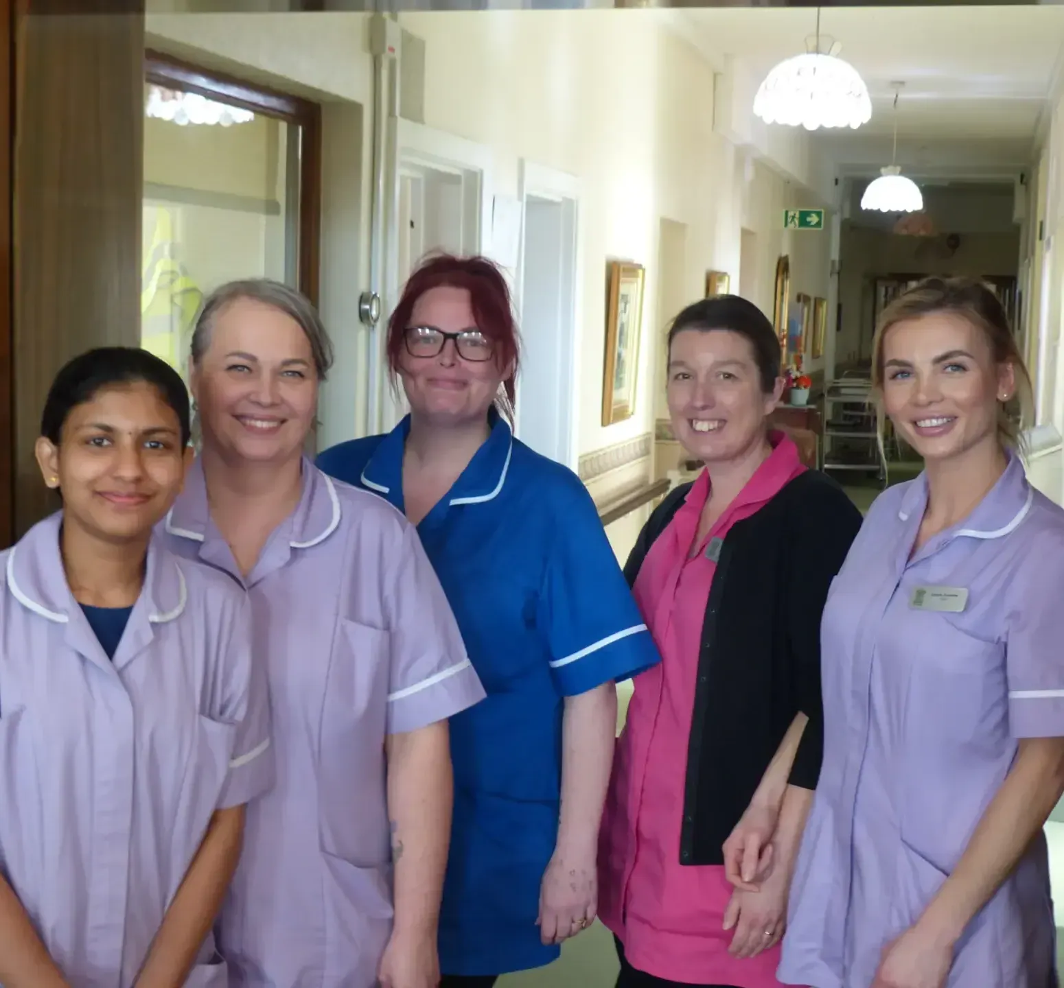 A group of nurses are posing for a picture in a hallway