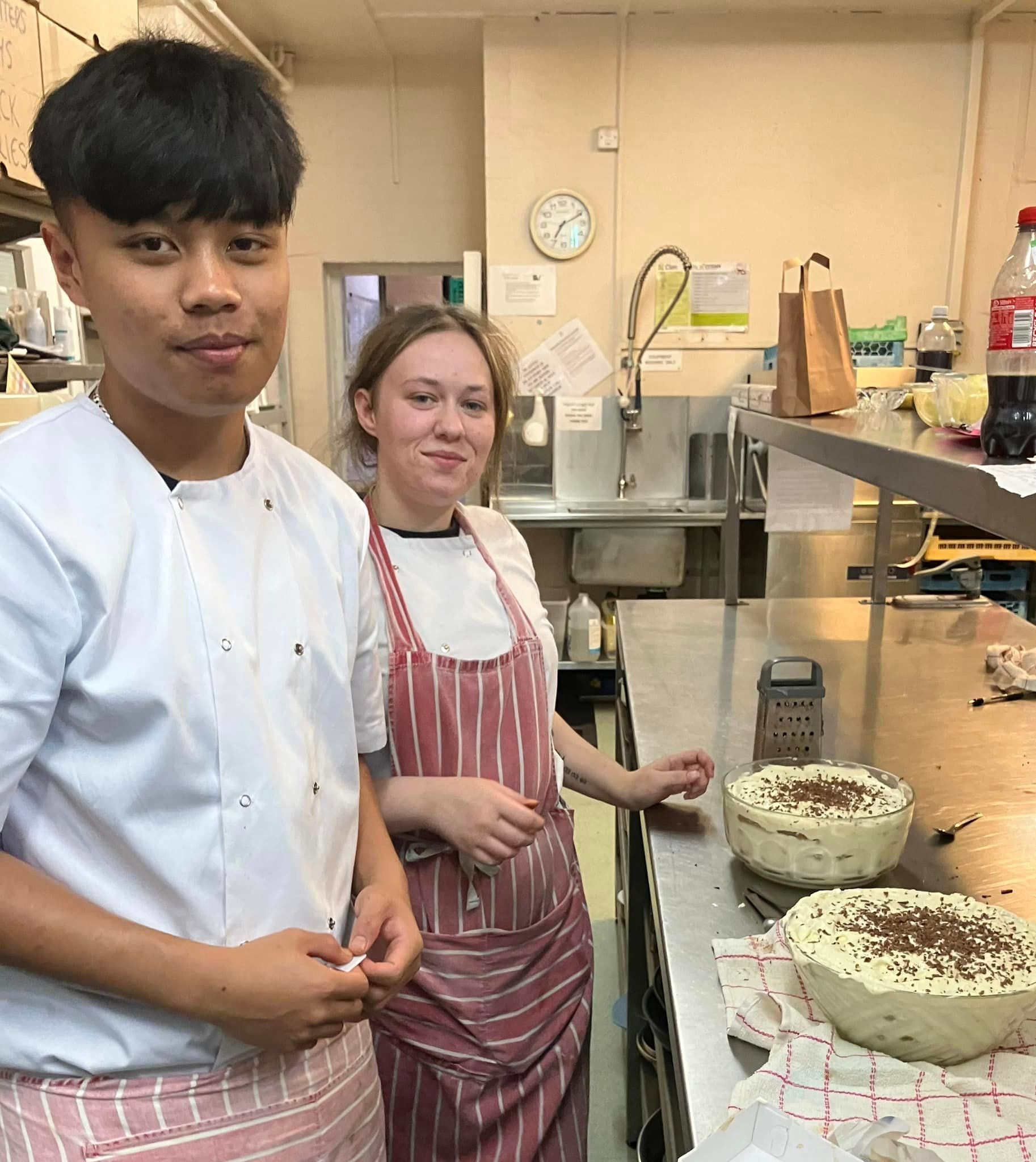 A man and a woman are standing next to each other in a kitchen.