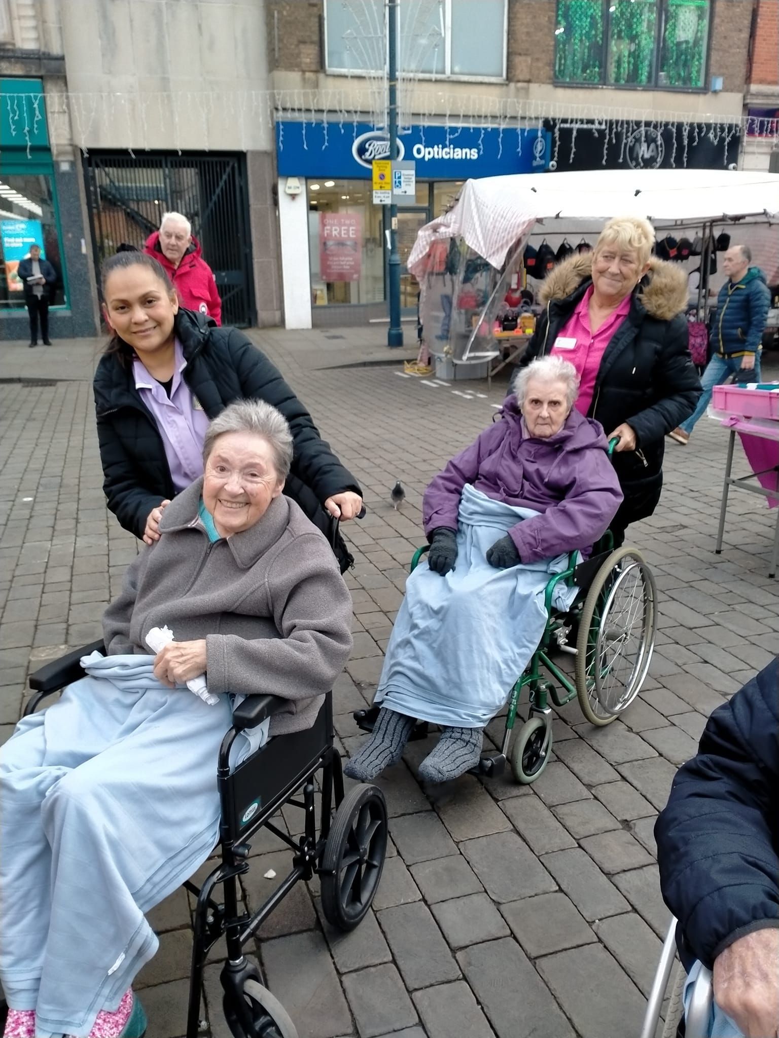 A group of people in wheelchairs are sitting on a brick sidewalk.
