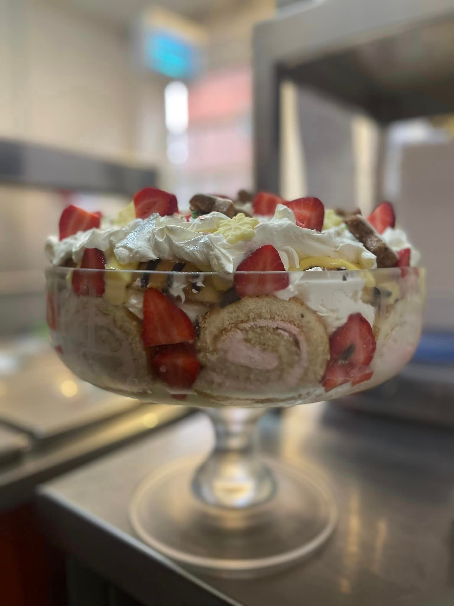 A glass bowl filled with strawberries and whipped cream on a table.