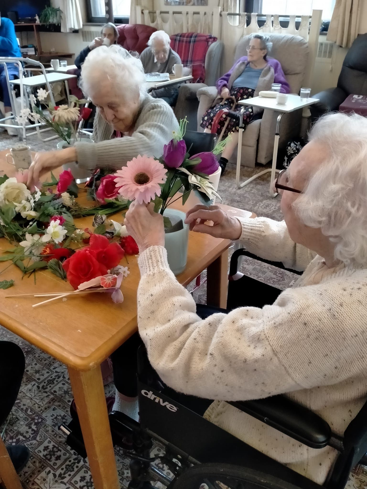 A group of elderly people are sitting around a table with flowers.