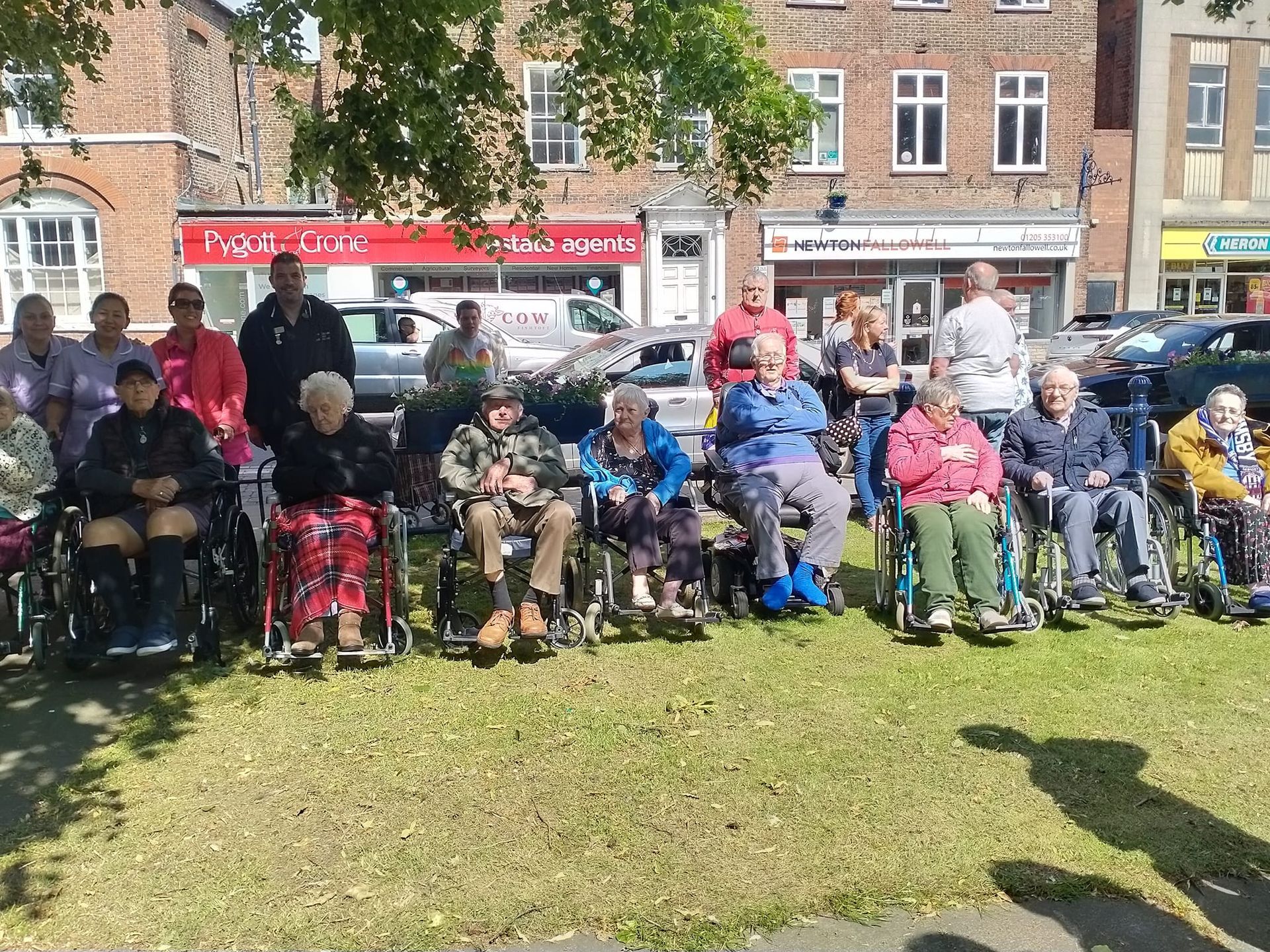 A group of people in wheelchairs are sitting in a park.