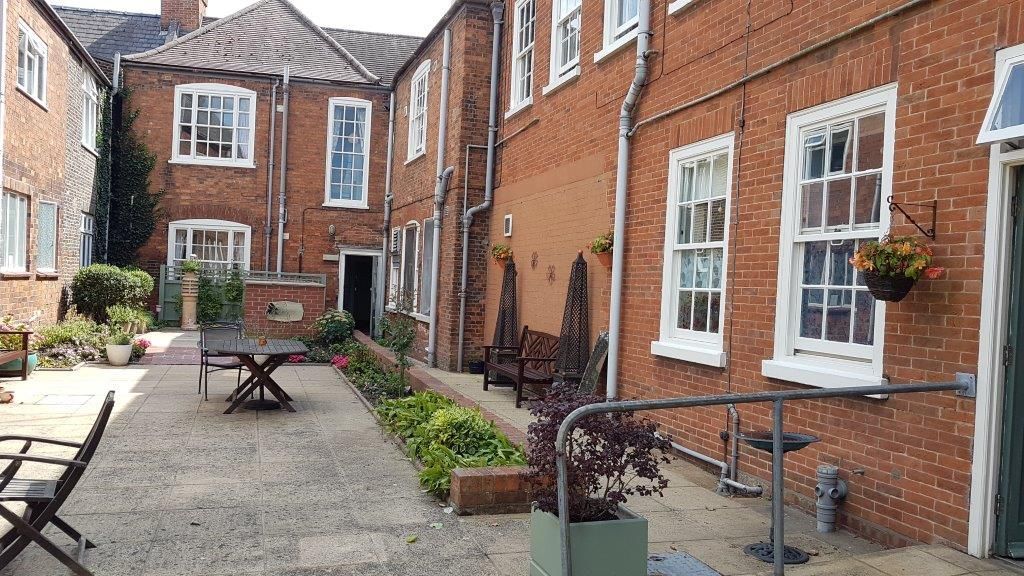 A courtyard with a table and chairs in front of a brick building.