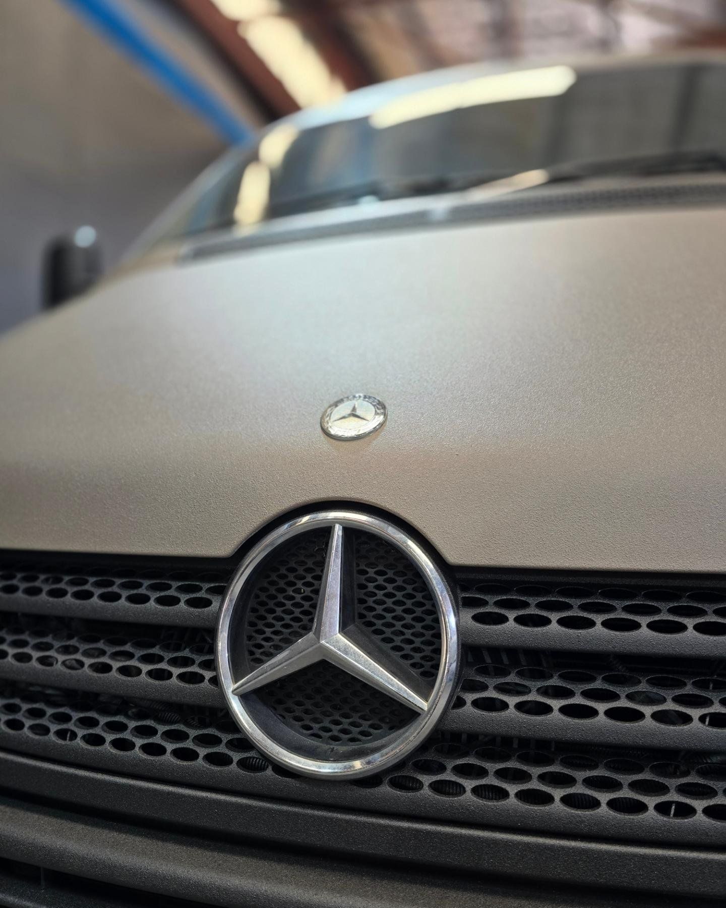 A close up of a mercedes logo on the hood