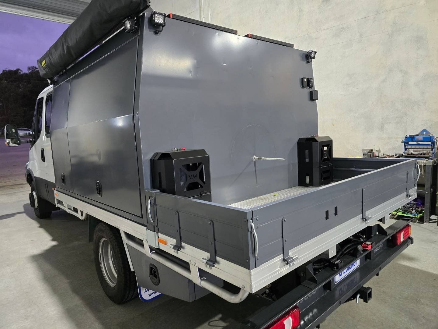 A gray truck with a roof rack is parked in a garage.