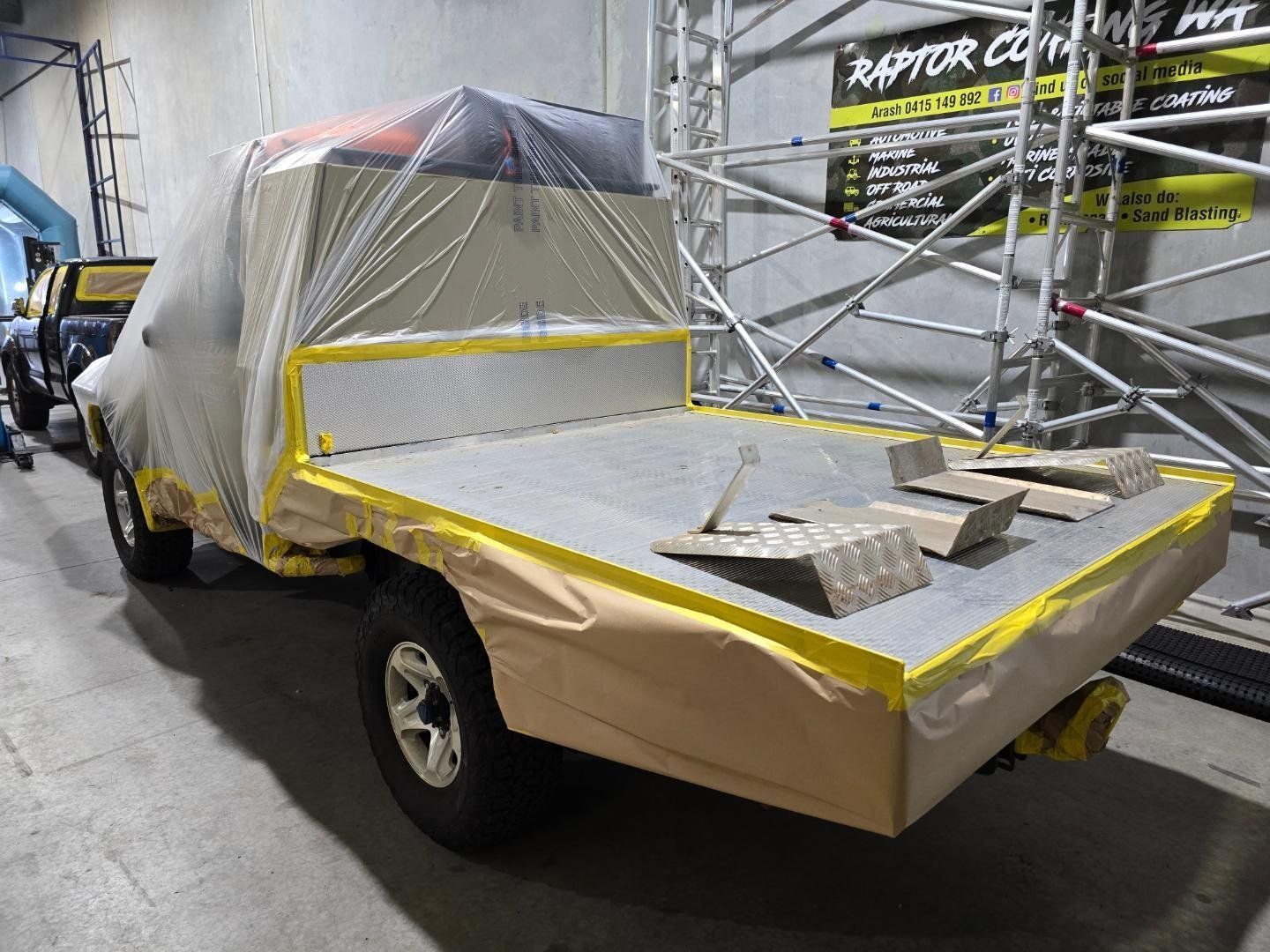 A truck is covered in plastic wrap in a garage.