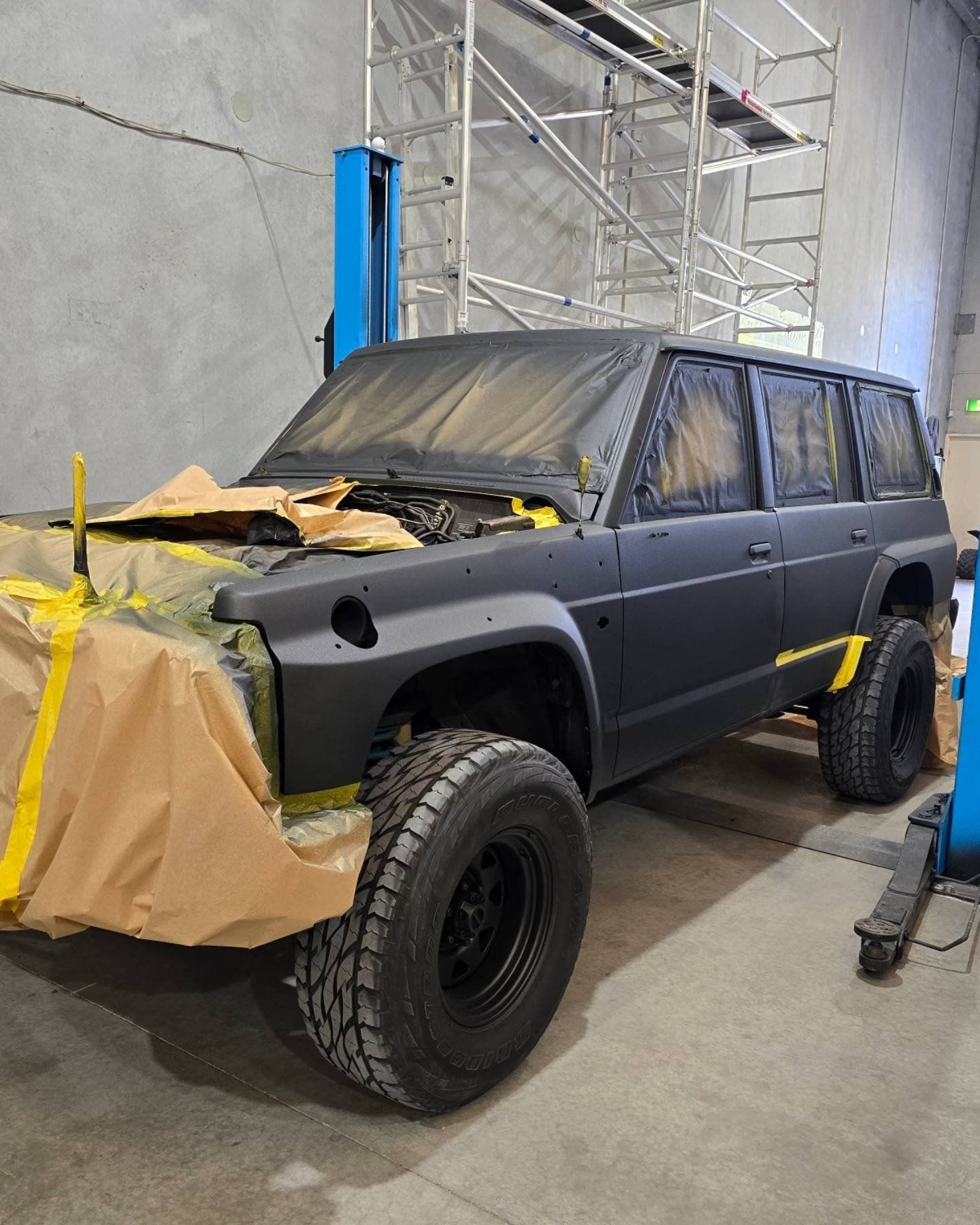 A black suv is being painted in a garage.