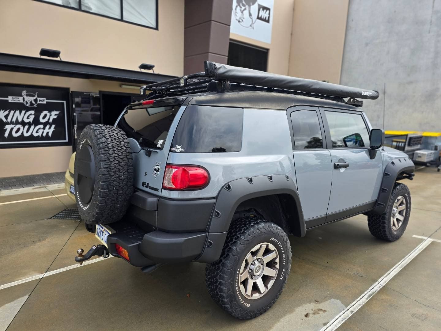 A toyota fj cruiser is parked in a parking lot in front of a building.