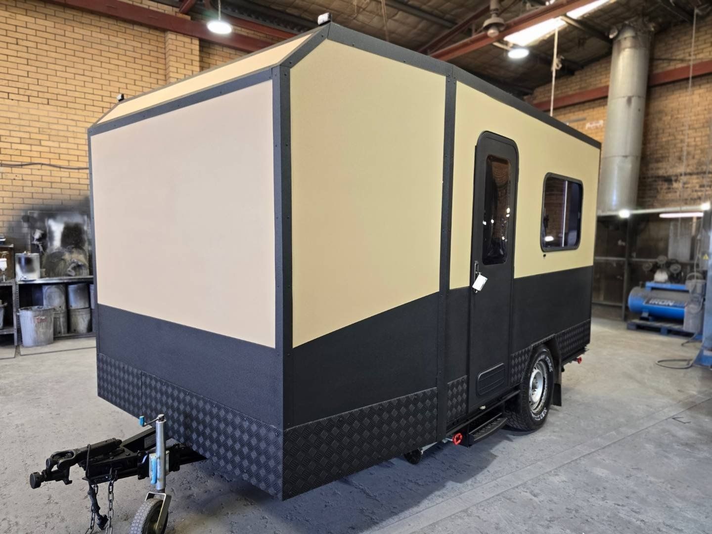 A small trailer is parked in a warehouse.