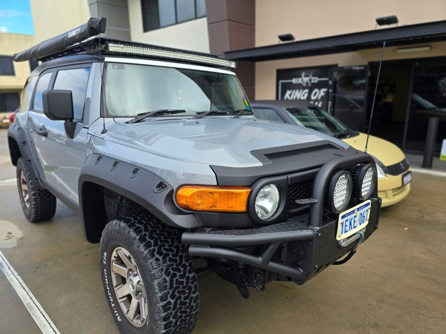 A toyota fj cruiser is parked in a parking lot next to a yellow car.