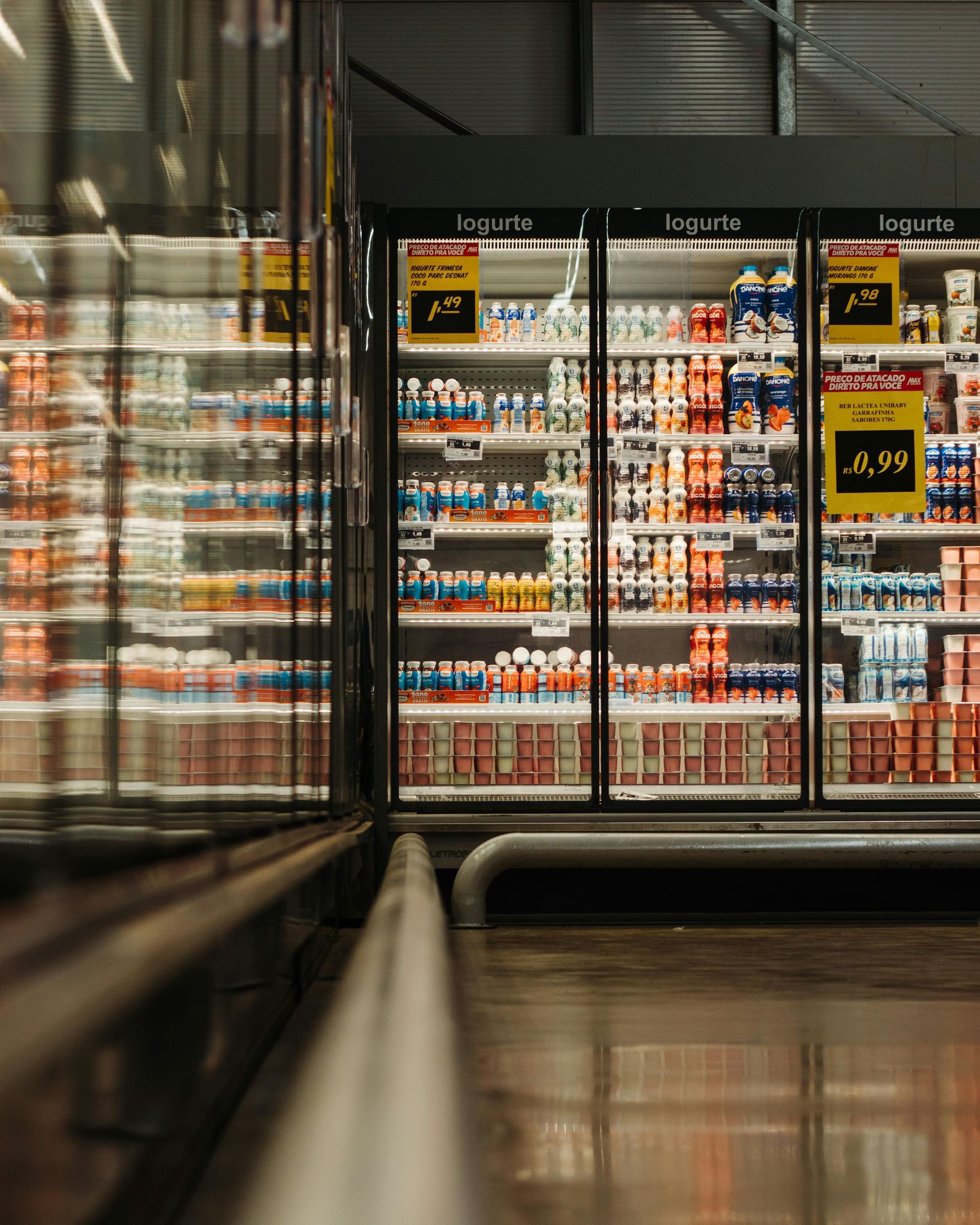 Refrigerated dairy aisle in a supermarket with various products, brightly lit.