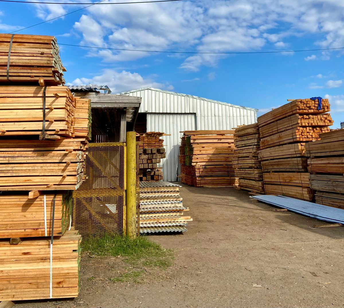 Pilas de tableros contrachapados de color oscuro sujetos con correas verdes en un almacén.