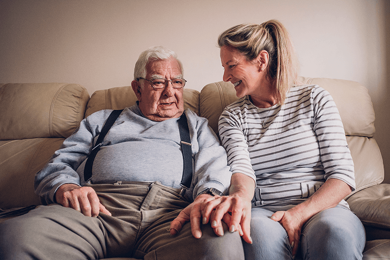 a senior man sitting with an adult child - daughter