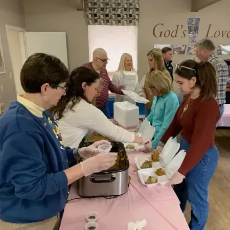 a group of people standing around a table with a sign on the wall that says god 's love