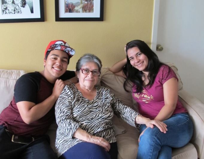 Two daughters are sitting with their mom on a couch.