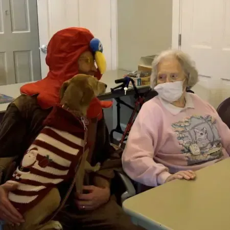 a man in a parrot costume is holding a dog
