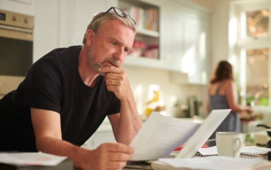 a man reading an invoice at a kitchen table