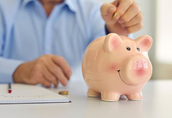 A senior putting money into a piggy bank to save for Independent Living