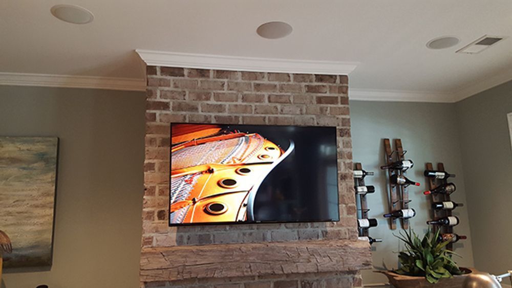 A flat screen tv is mounted on a brick wall in a living room.
