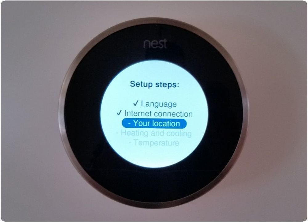 A nest thermostat is displaying the setup steps