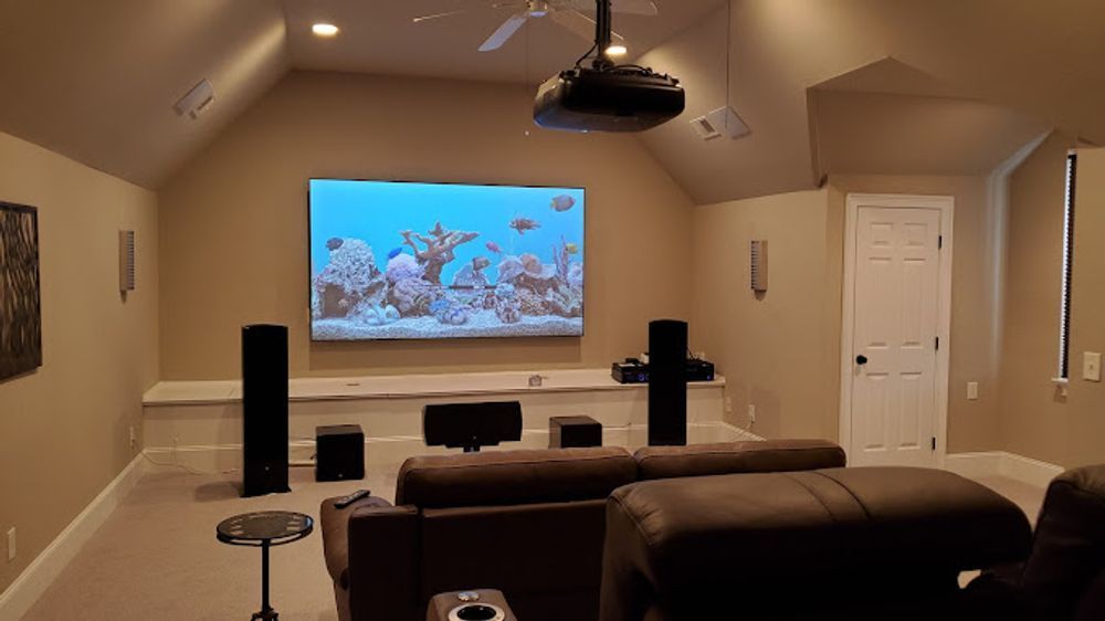 A home theater with a projector and a flat screen tv on the wall.