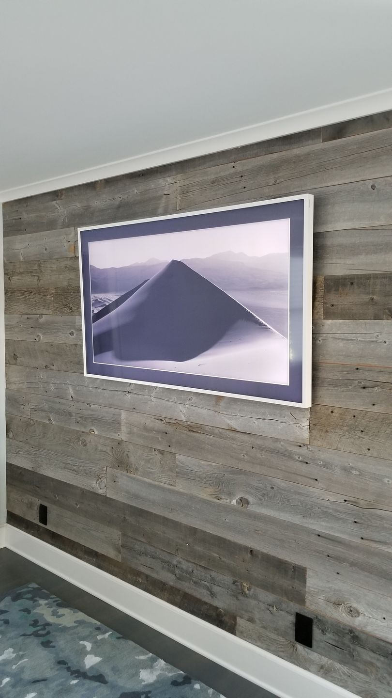 A flat screen tv is hanging on a wooden wall.