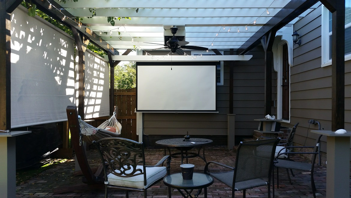 A projector screen is hanging from the ceiling of a pergola