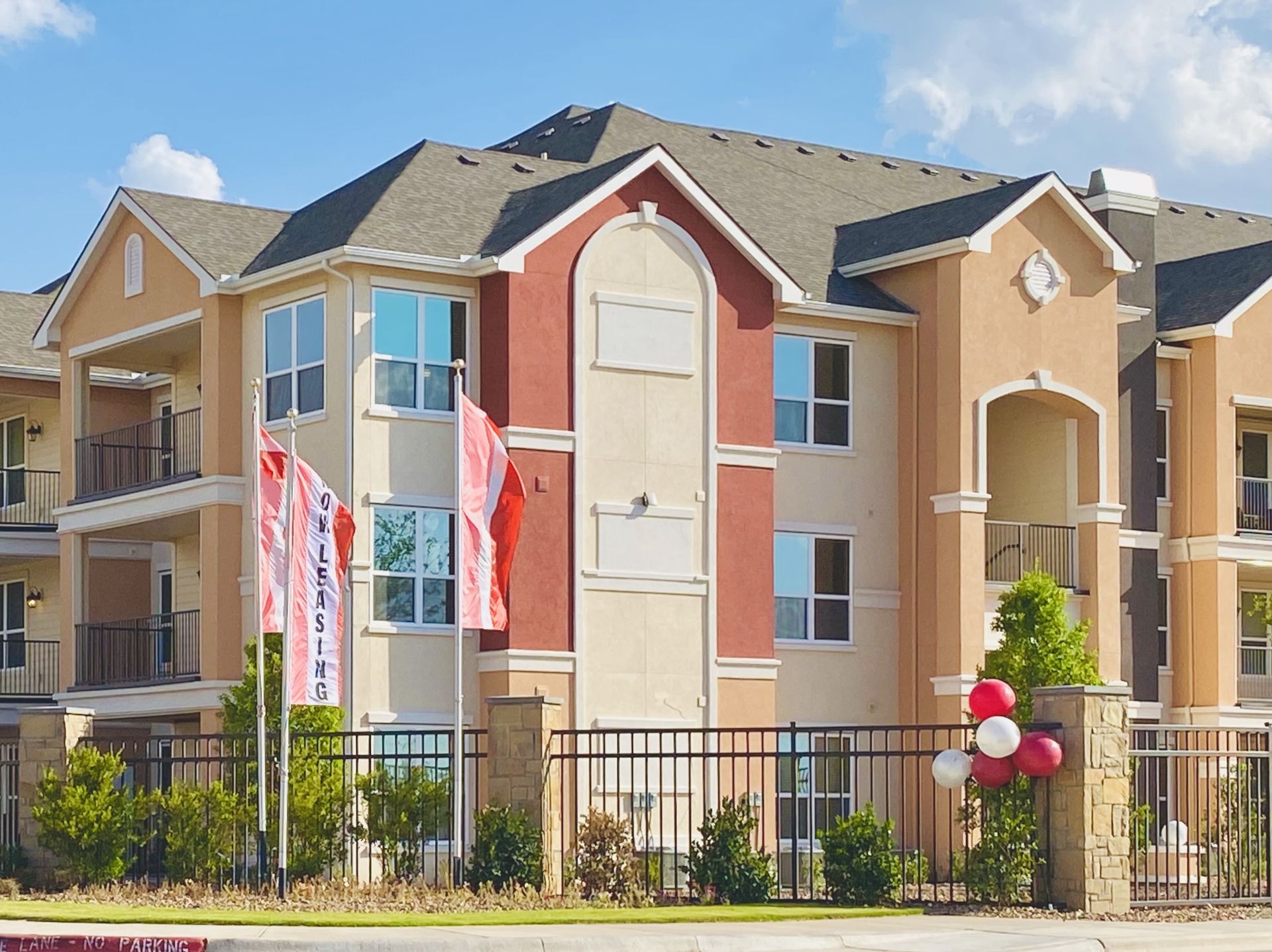A large apartment building with red white and blue balloons in front of it