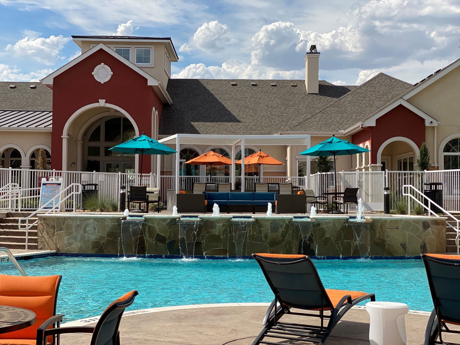 A large swimming pool with chairs and umbrellas in front of a building.