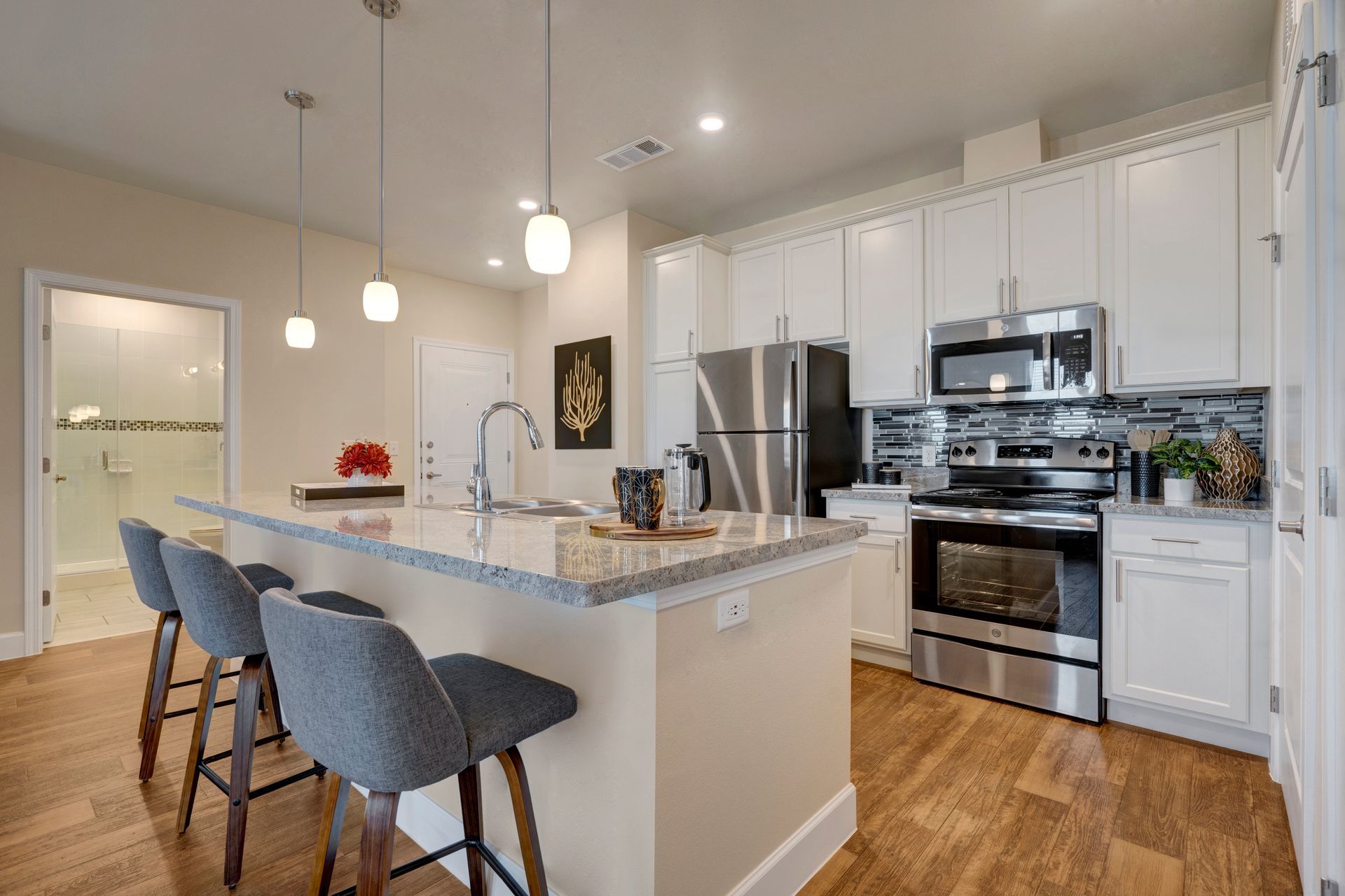 A kitchen with white cabinets , stainless steel appliances , and a large island.