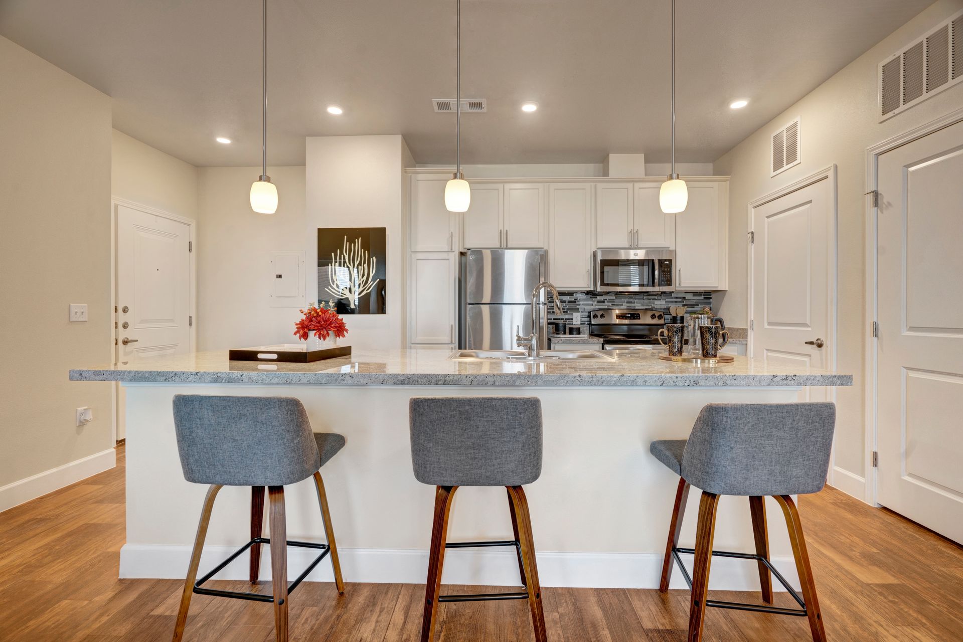 A kitchen with a large island and three bar stools.