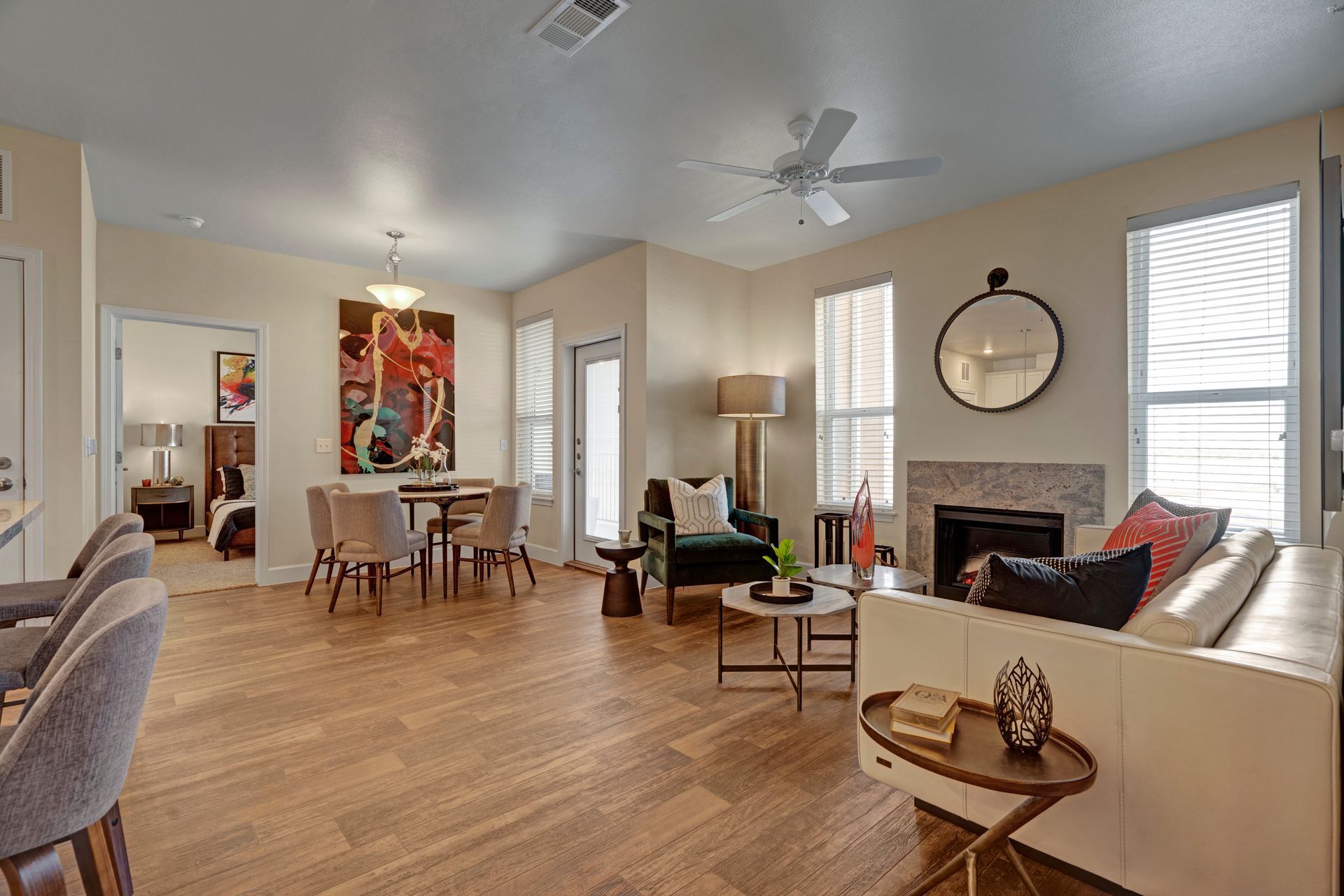 A living room with a couch , chairs , a fireplace and a ceiling fan.